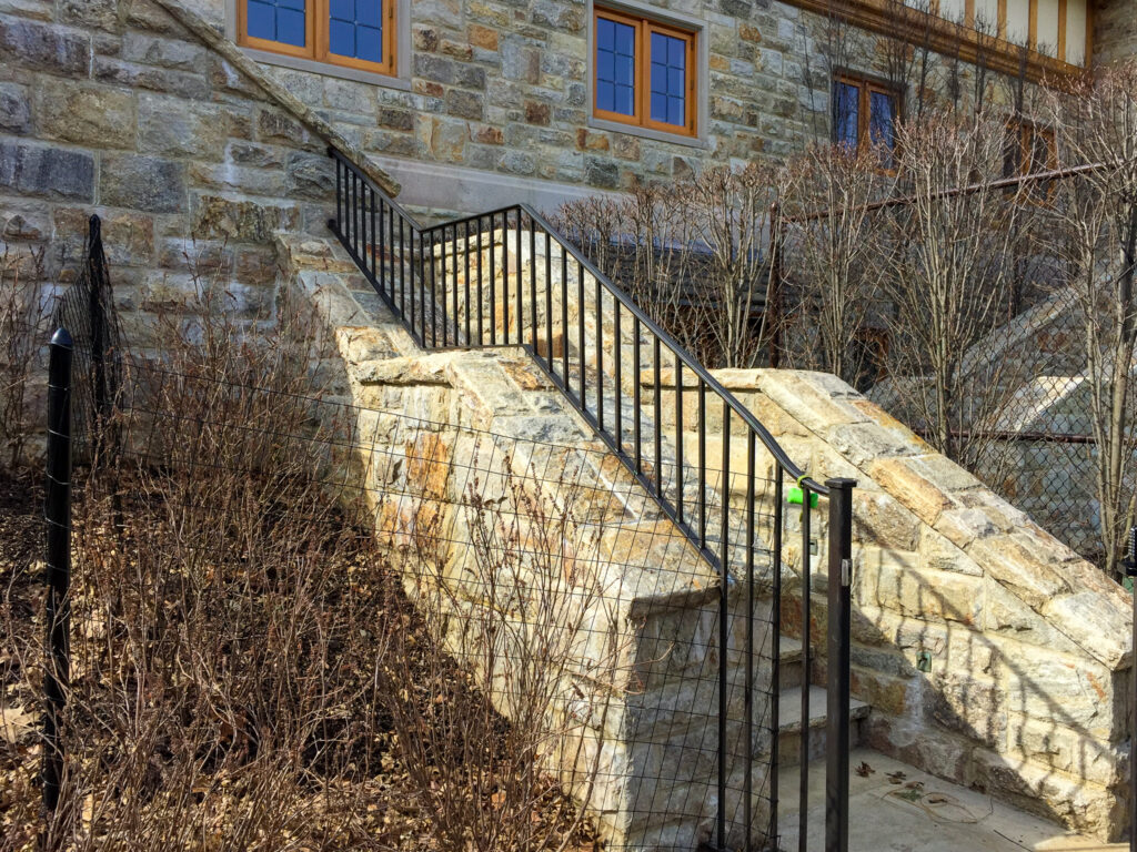 A half stone wall is topped with a simple half wrought iron railing on one side.