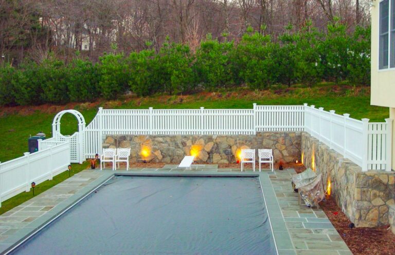 Picket style white wood fence surrounding a pool